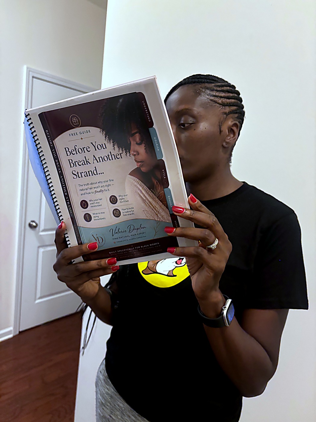 Valerie Duplan holding her free guide, Before You Break Another Strand, for fine natural hair